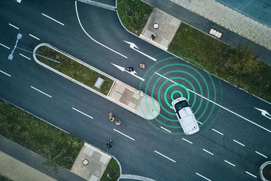 Overhead view of a car at a road junction with green sensor rings extending towards pedestrians
